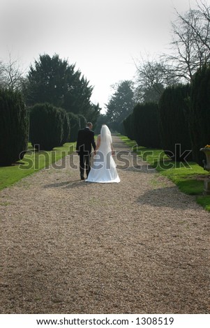 Bride and Groom walking away down a tree lined gravel path