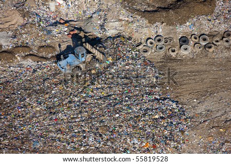 An aerial image of a large bulldozer spreading rubbish at a waste dump.