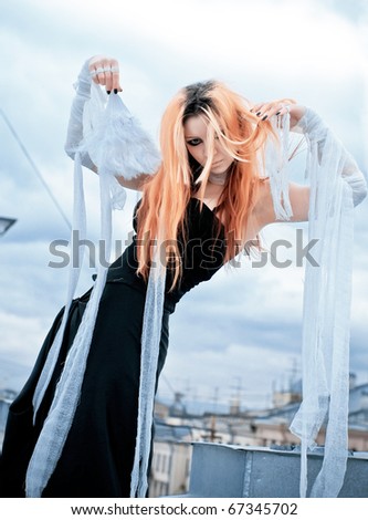 photo of a Pretty red-haired girl with feathers, bandages and fan on rooftop