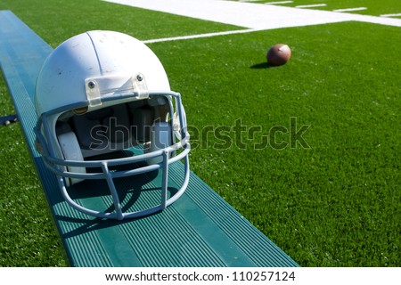 American Football Helmet on the Bench with the field and ball beyond