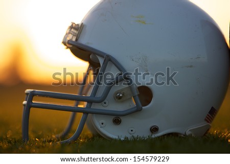American Football Helmet on the Field backlit by the Sunset