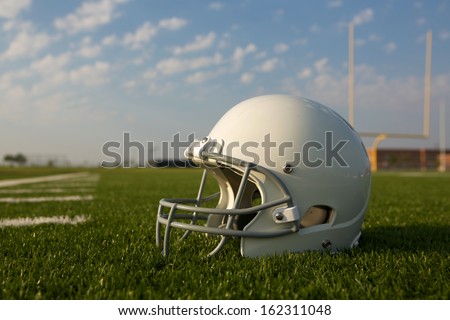 American Football Helmet on the Field with Goal Posts Beyond