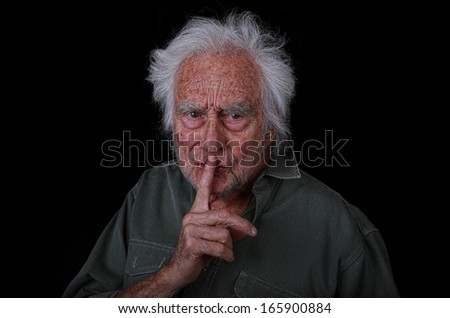 Portrait of a Senior Man with a Angry Expression on black background asking someone to be quiet