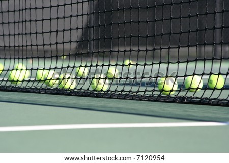 Tennis court net with many tennis balls behind