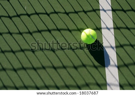 Tennis ball on the court in the shadow of the net