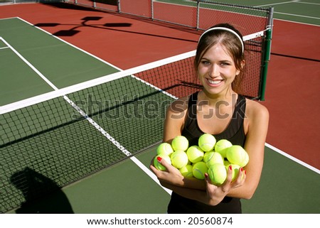 Happy brunette tennis woman holding a bunch of tennis balls