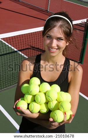 Brunette female tennis athlete holding a lot of tennis balls