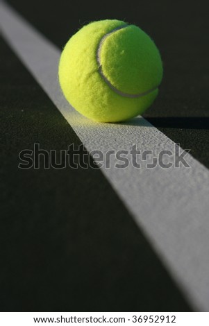 Tennis ball on a court line with room for copy in the foreground