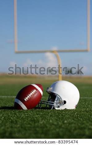American Football and Helmet with the Goal Posts in the background