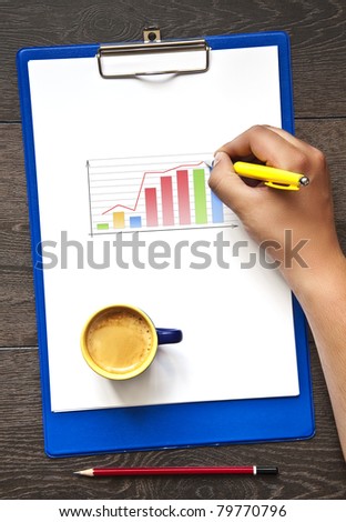 Hand with pen writing  on the clipboard and graph on it