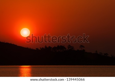 Orange sunrise over island. Warm colors. Calm sea.