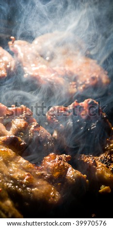 Chicken meat smoking while being cooked on barbecue