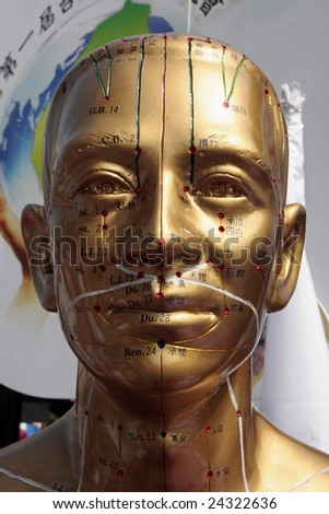 Human acupuncture point displayed by golden sculpture.