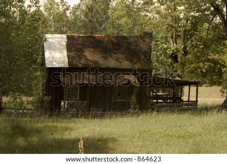 An old cabin in a clearing.Deserted? Look at the wood pile on the porch.