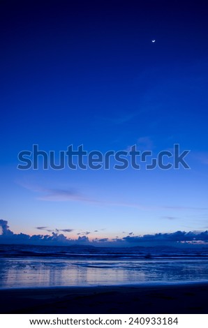 Twilight beach scene with moon on sky