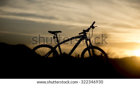 Silhouette of mountain bike with sunset light, Cycling for travel concept