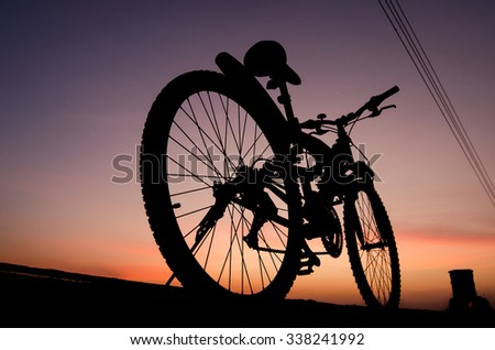 Silhouette of mountain bike parking on jetty beside sea with sunset sky background