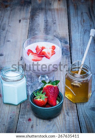 Fresh strawberry smoothie in a glass. Strawberries, yogurt and honey in jars.