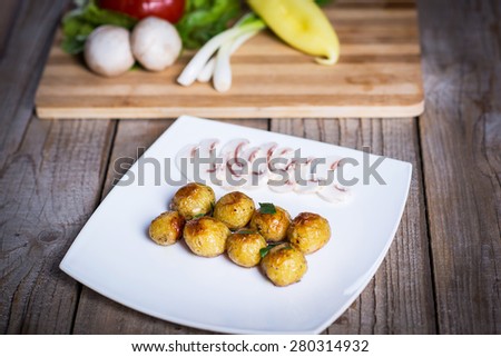 Baked or roasted potatoes on a plate with mushroom slices and fresh veggies