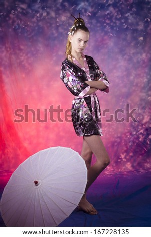young teenage girl in floral kimono standing near white umbrella  in studio