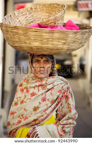 UDAIPUR, INDIA - JANUARY 25: Unidentified Indian woman carries a basket of saris on January 25, 2011 in Udaipur, India. Saris are the dresses that Indian women wear.