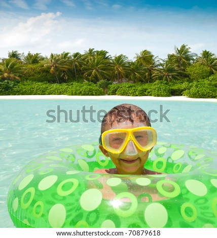 Young boy playing with mask and tube in the tropical ocean water. Maldive Islands.