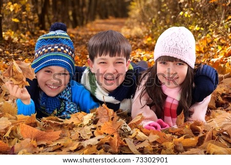 Brothers and sister playing outside in Autumn leaves.