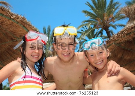 Three siblings in bathing suits, snorkels and diving masks.