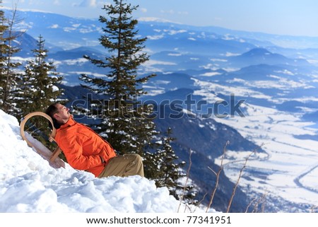 A man resting on the top of a snow covered mountain.