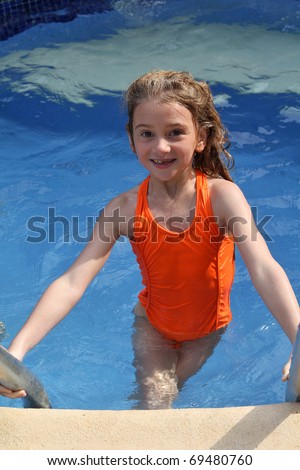 Young girl climbs out of pool after swimming