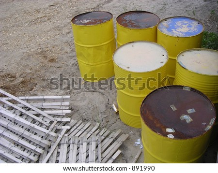 Six Yellow Rusted Barrels with fence on the beach