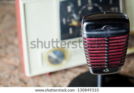 Looking down on a vintage chrome microphone with a vintage clock radio in the background