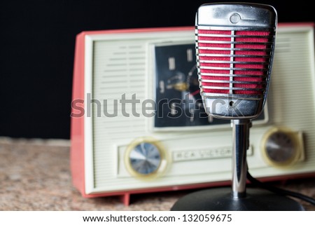 Vintage chrome and red microphone with a vintage 50\'s style radio in the background