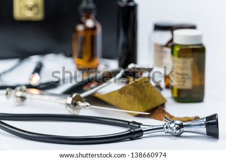 A gathering of antique doctors instruments and tools along with a black vintage doctors bag