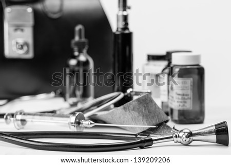 A gathering of vintage and antique medical instruments and tools with a old leather doctors bag in the background