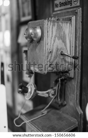 Black and white shot of an antique wall mount hand crank wooden telephone