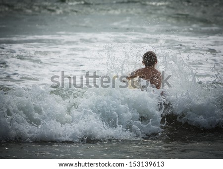 Young boy crashing through white water wave on a yellow boogie board at Sunset Beach in Southern California
