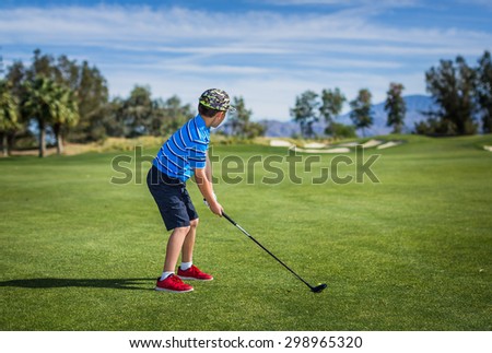 Wide shot of a young boy about to tee off at a beautiful golf course in Rancho Mirage, California