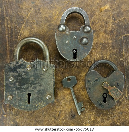 Three antique locks and a key on an aged leather background