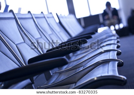 Row of modern chairs at the airport with person waiting at the gate