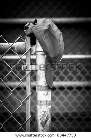 black and white of an old baseball hat hanging on the dugout post
