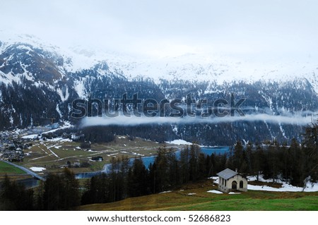 A small house with iced lake and Swiss Alps background in St. Moritz, Switzerland.