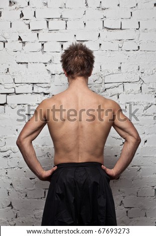 Strong muscular man back at  white wall background