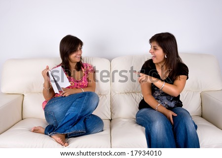 twin sisters in sofa talking about a book