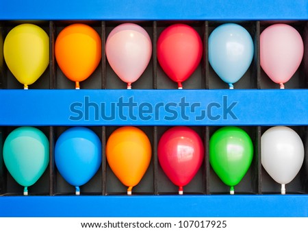 A blue wall case with colorful balloons. Photo is of a boardwalk arcade game. Only the case and balloons are shown.