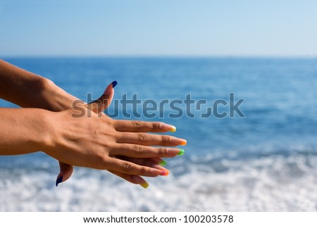 Beautiful woman hands with a manicure at the background of the sea