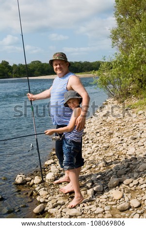 Joyful grandfather and grandson go fishing on the river.