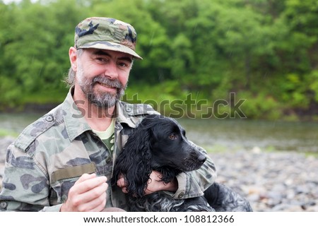 Middle aged man with a dog (Russian Hunting Spaniel). At the river. Rain.