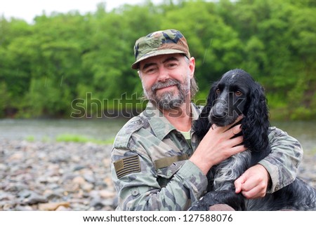 Middle aged man with a dog (Russian Hunting Spaniel). At river in the rain.