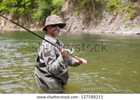 Joyful Fisherman catches of salmon in a mountain river.